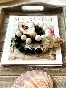 boho white and black beads coastline with gilded oyster shell. lifestyle wrapped on magazine shot